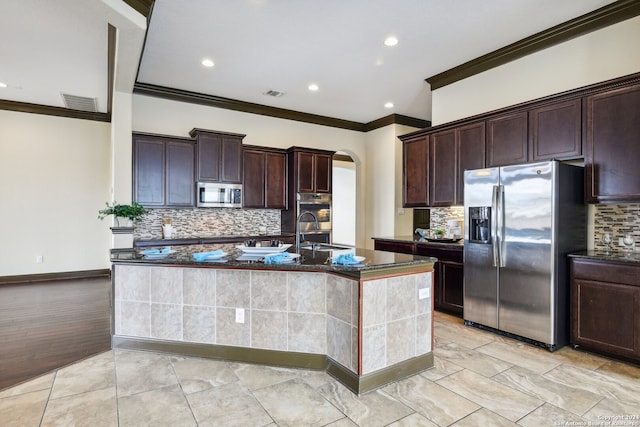 kitchen featuring stainless steel appliances, a center island with sink, decorative backsplash, and ornamental molding