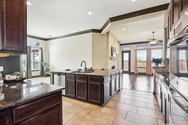 kitchen featuring sink, a kitchen island with sink, ornamental molding, stainless steel dishwasher, and light wood-type flooring