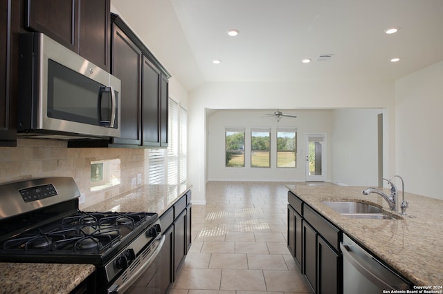 kitchen featuring stainless steel appliances, sink, light tile patterned flooring, backsplash, and light stone countertops