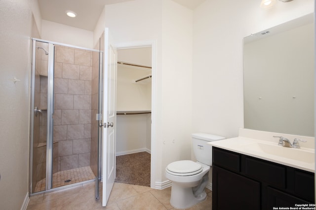 bathroom featuring tile patterned flooring, vanity, toilet, and a shower with door