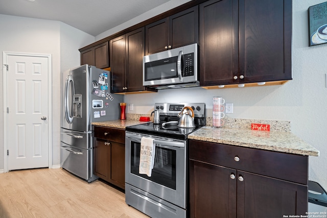 kitchen featuring stainless steel appliances, light wood-type flooring, light stone counters, and dark brown cabinetry