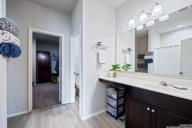 bathroom featuring vanity, hardwood / wood-style flooring, toilet, and a shower with shower curtain