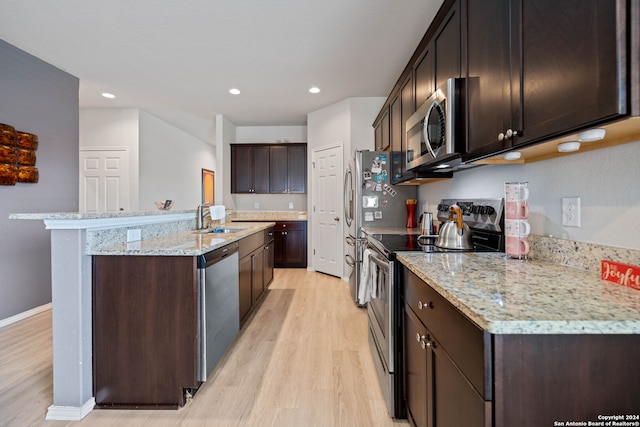 kitchen featuring stainless steel appliances, light hardwood / wood-style floors, dark brown cabinetry, sink, and a kitchen island with sink