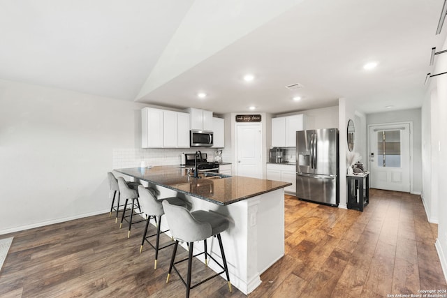 kitchen featuring stainless steel appliances, sink, a breakfast bar, kitchen peninsula, and white cabinets