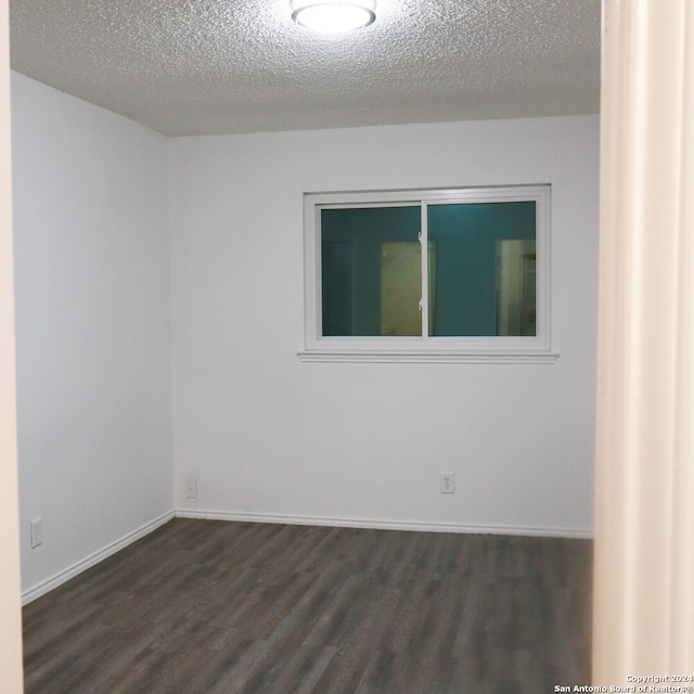 empty room with a textured ceiling and dark hardwood / wood-style floors