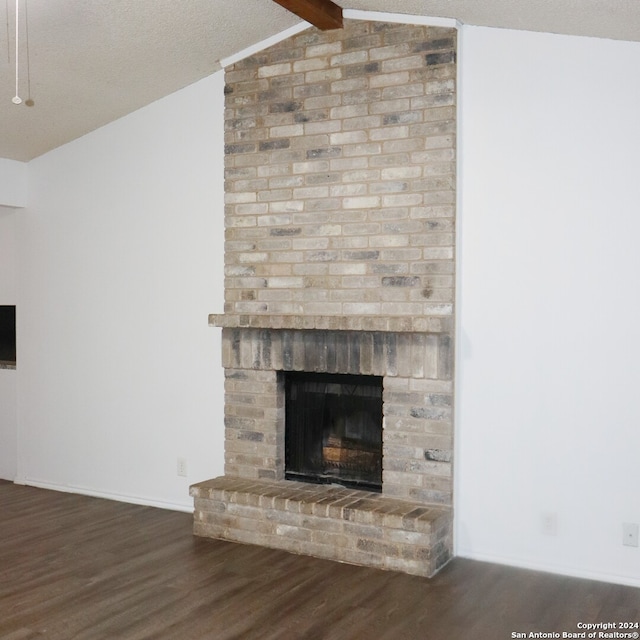 room details featuring a textured ceiling, hardwood / wood-style flooring, a brick fireplace, and beam ceiling