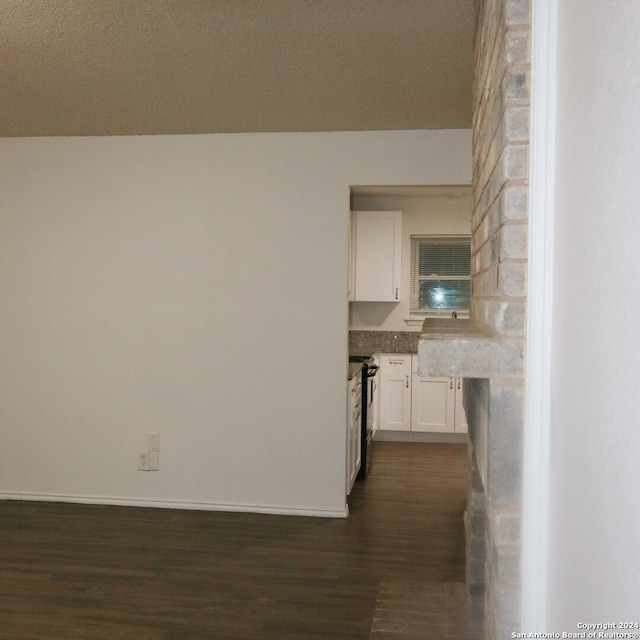 kitchen with white cabinetry, black electric range oven, a textured ceiling, and dark hardwood / wood-style flooring