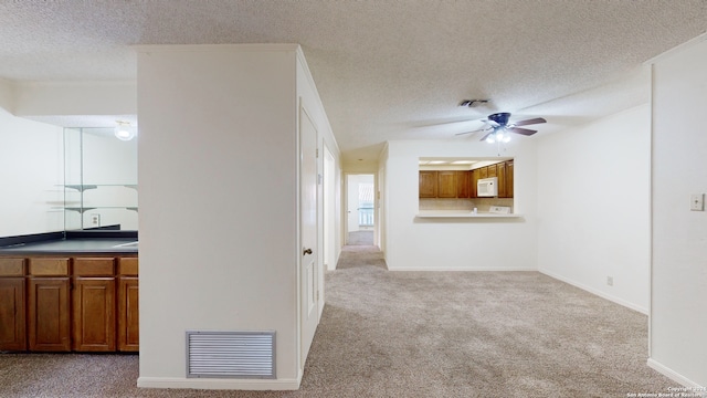 unfurnished living room with ceiling fan, a textured ceiling, and light carpet