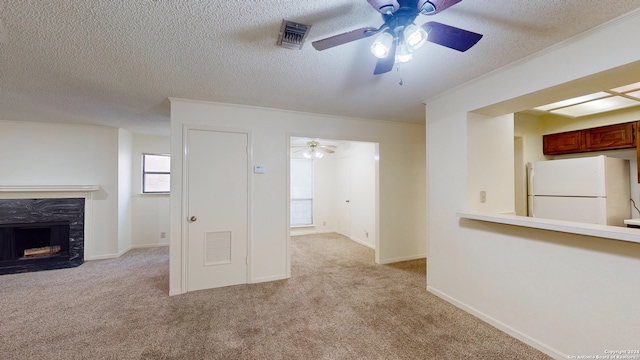 unfurnished living room featuring a fireplace, light colored carpet, a textured ceiling, and ceiling fan