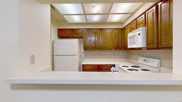 kitchen featuring kitchen peninsula, white appliances, and backsplash