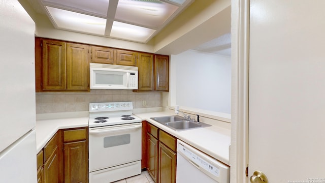 kitchen with light tile patterned floors, white appliances, sink, and backsplash