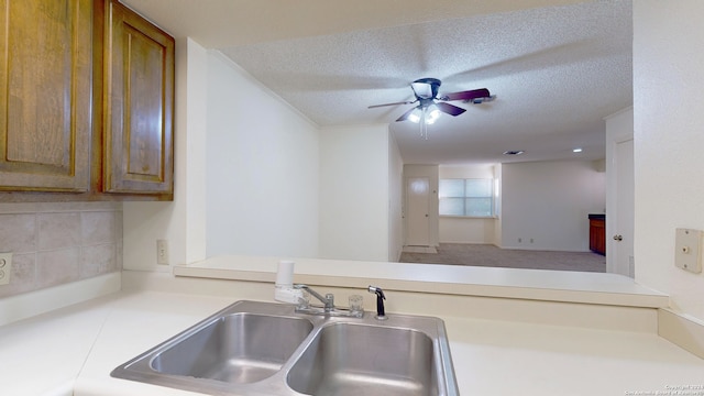 kitchen with a textured ceiling, sink, and ceiling fan