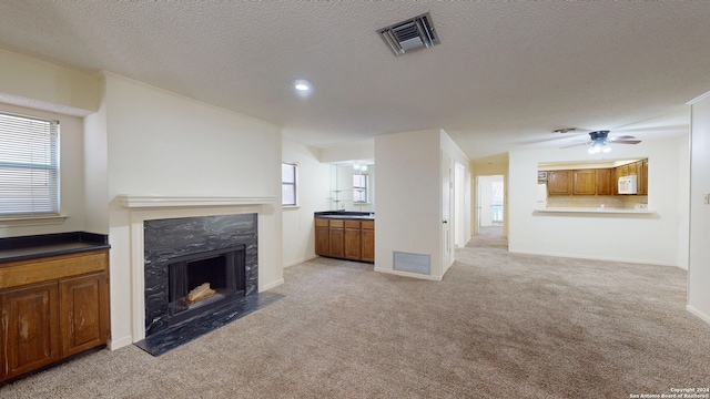 unfurnished living room featuring a fireplace, light carpet, and ceiling fan