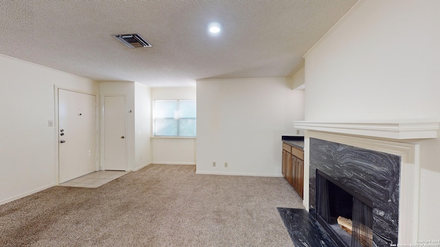 unfurnished living room featuring a textured ceiling, a premium fireplace, and light carpet