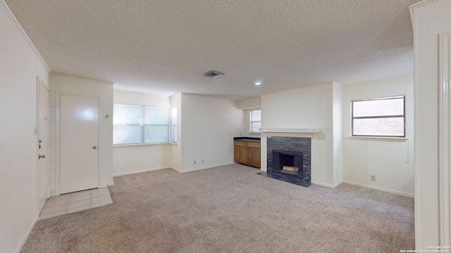 unfurnished living room with a fireplace, a healthy amount of sunlight, light carpet, and a textured ceiling