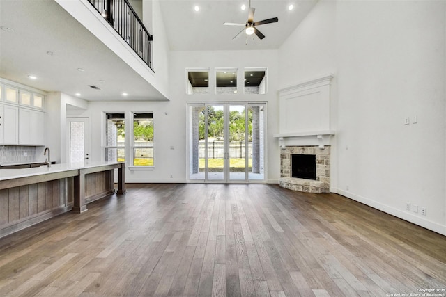 228 Dulce, Boerne, TX 78006 - unfurnished living room featuring a high ceiling, ceiling fan, wood finished floors, a fireplace, and baseboards