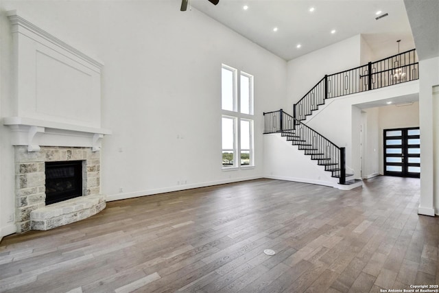 228 Dulce, Boerne, TX 78006 - unfurnished living room featuring a towering ceiling, wood finished floors, ceiling fan, stairs, and baseboards