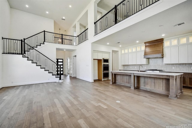 228 Dulce, Boerne, TX 78006 - kitchen featuring custom range hood, light countertops, light wood finished floors, white cabinetry, and a high ceiling