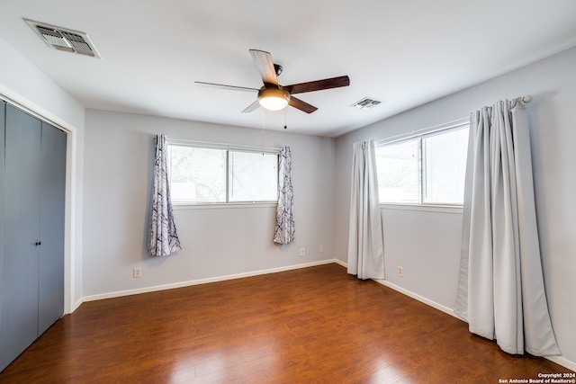 empty room with a wealth of natural light, dark hardwood / wood-style floors, and ceiling fan