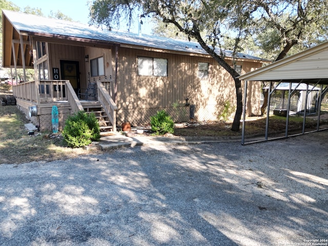 rear view of property featuring covered porch and a carport