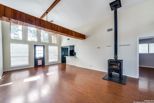 unfurnished living room with dark wood-type flooring, beamed ceiling, a wood stove, and high vaulted ceiling