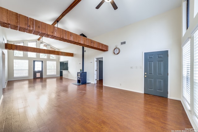 unfurnished living room featuring hardwood / wood-style flooring, beamed ceiling, ceiling fan, high vaulted ceiling, and a wood stove