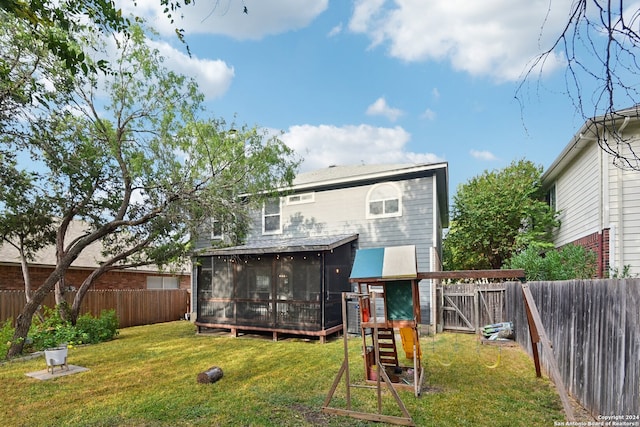 back of property featuring a playground, a sunroom, and a yard