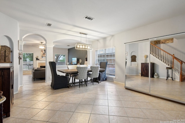 dining space featuring light tile patterned flooring and ceiling fan with notable chandelier