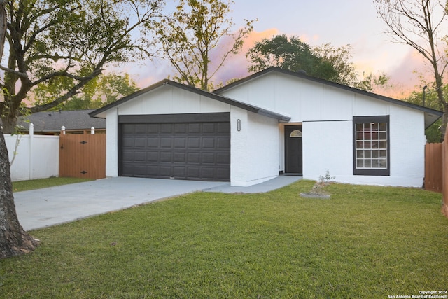 ranch-style home featuring a garage and a lawn