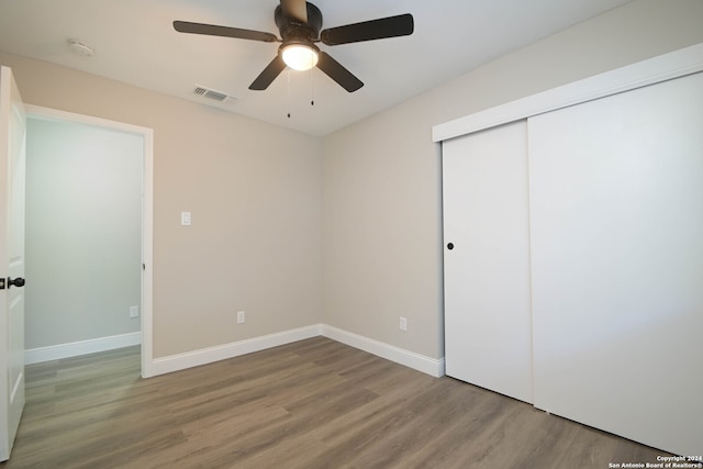 unfurnished bedroom featuring ceiling fan, a closet, and wood-type flooring