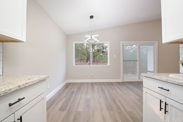 unfurnished dining area featuring light hardwood / wood-style flooring, a chandelier, and vaulted ceiling