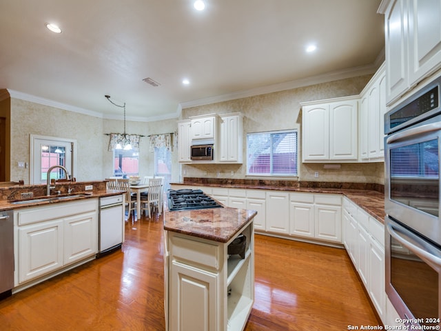 kitchen with stainless steel appliances, decorative light fixtures, sink, a healthy amount of sunlight, and white cabinets