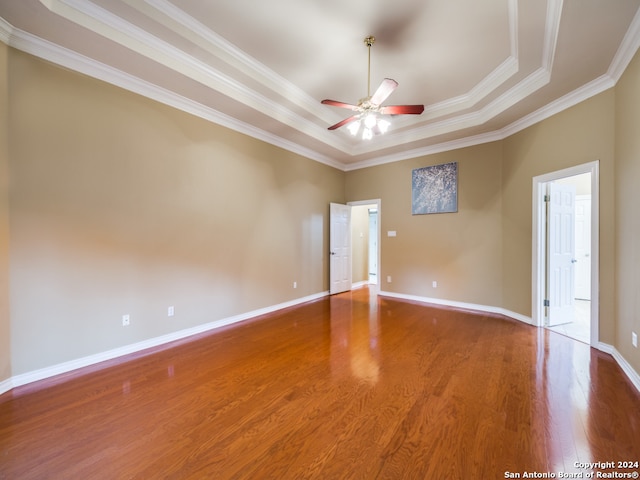 empty room with ceiling fan, hardwood / wood-style floors, ornamental molding, and a raised ceiling