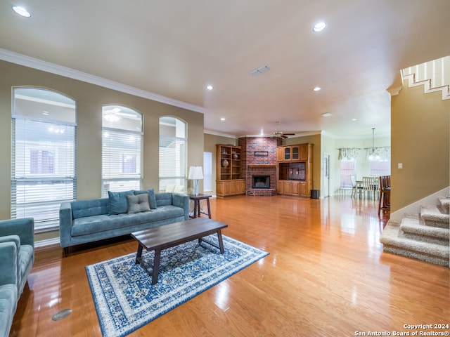 living room with hardwood / wood-style floors, ornamental molding, and a brick fireplace