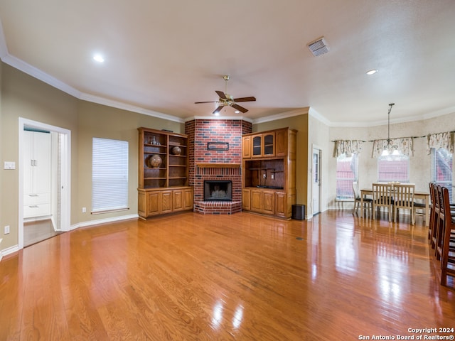 unfurnished living room featuring light hardwood / wood-style floors, ornamental molding, and ceiling fan with notable chandelier