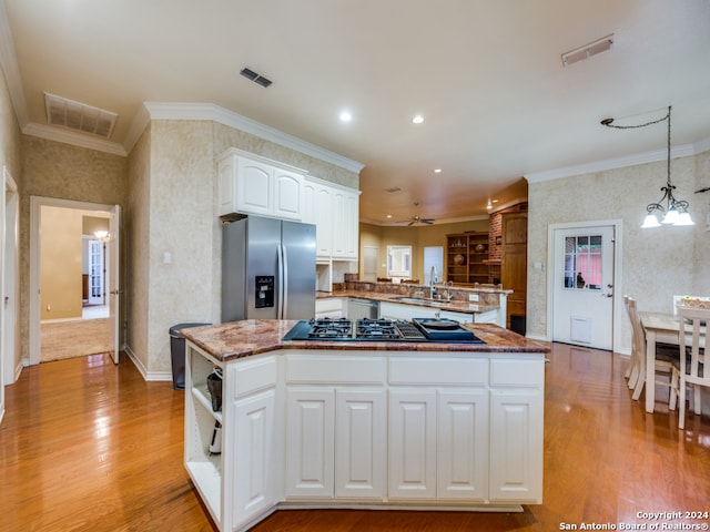 kitchen with sink, kitchen peninsula, white cabinets, stainless steel fridge, and pendant lighting