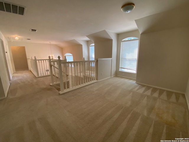 bonus room with light colored carpet and a chandelier