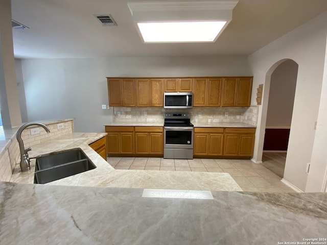 kitchen with tasteful backsplash, appliances with stainless steel finishes, sink, and light tile patterned floors