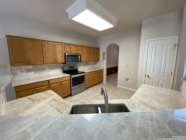 kitchen featuring backsplash, appliances with stainless steel finishes, sink, and light tile patterned floors