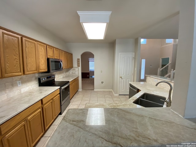 kitchen featuring light tile patterned flooring, sink, backsplash, and appliances with stainless steel finishes