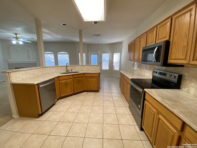 kitchen with a wealth of natural light, appliances with stainless steel finishes, sink, and decorative light fixtures