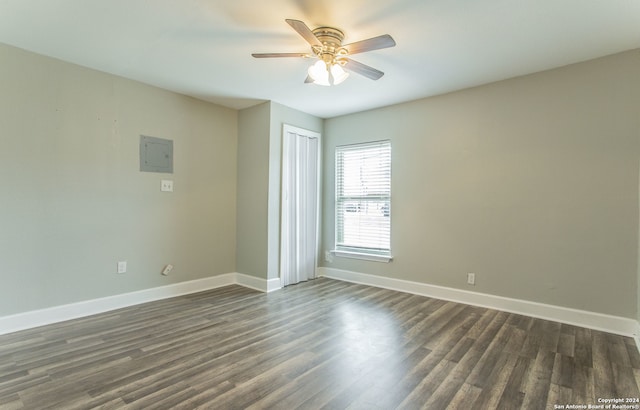 unfurnished room with electric panel, ceiling fan, and dark hardwood / wood-style flooring