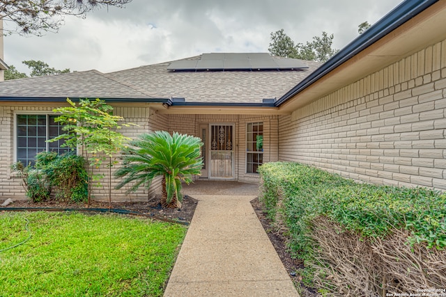 property entrance featuring solar panels and a lawn