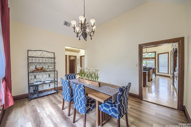 dining space featuring an inviting chandelier, high vaulted ceiling, and light wood-type flooring