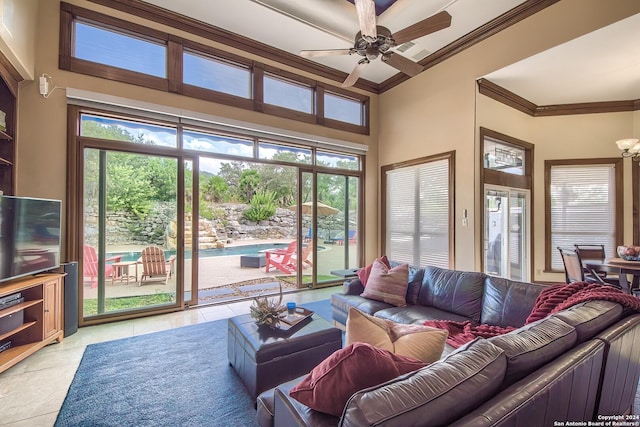 living room featuring light tile patterned floors, ornamental molding, ceiling fan, and a high ceiling