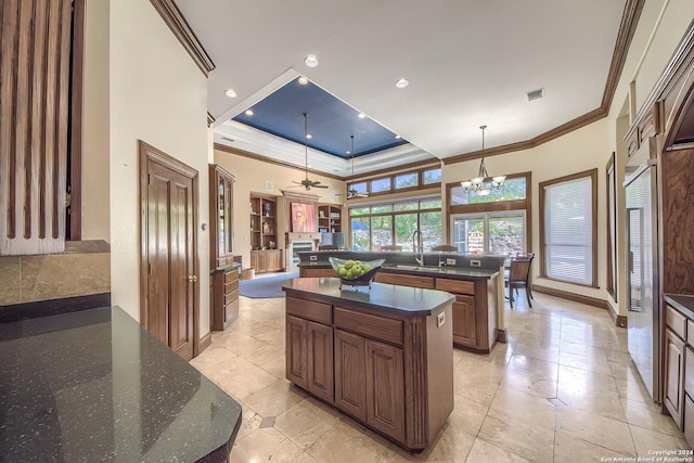 kitchen featuring pendant lighting, sink, crown molding, a kitchen island with sink, and a raised ceiling