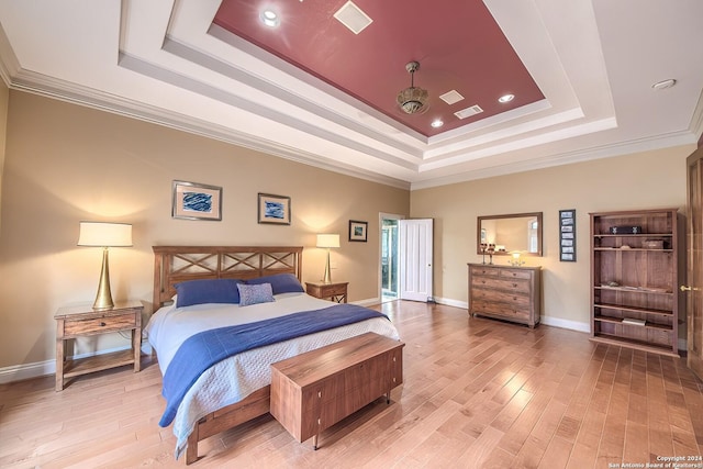 bedroom featuring crown molding, a raised ceiling, and light wood-type flooring