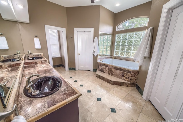 bathroom with a relaxing tiled tub, vanity, and tile patterned flooring