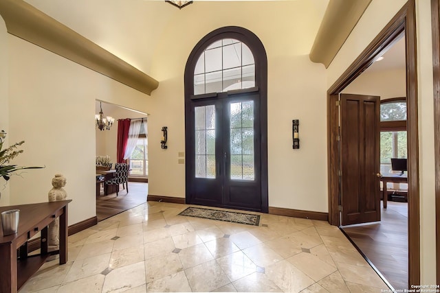 foyer entrance with a towering ceiling, an inviting chandelier, and french doors