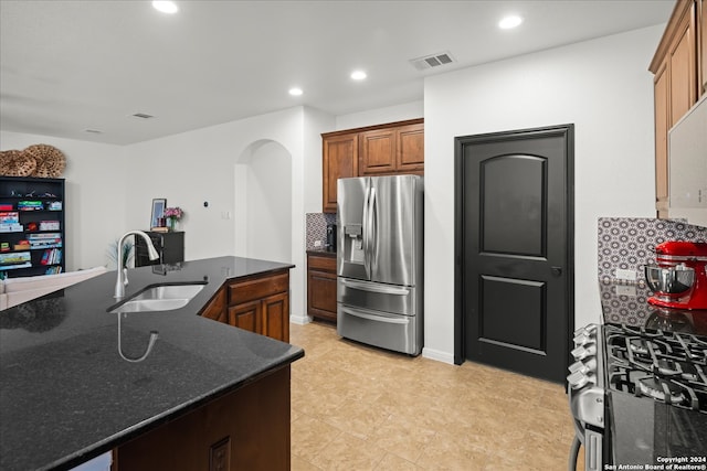 kitchen featuring appliances with stainless steel finishes, dark stone counters, sink, and backsplash